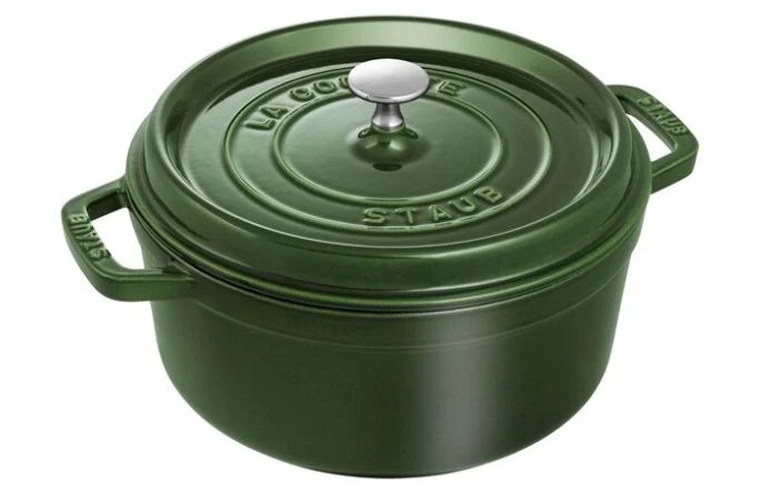 A green cast iron Dutch oven with a silver knob and embossed lettering on the lid.