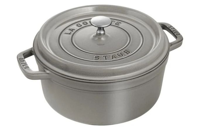 A round, gray cast iron Dutch oven with a lid and side handles, labeled "LA COCOTTE STAUB."